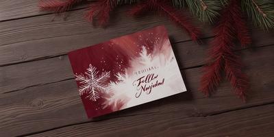 The primary subject of the image is a card with a snowflake pattern on it. The card is placed on a wooden table, which serves as the setting. The visual style of the card is a combination of digital art and illustration, creating a festive and holiday-themed appearance. The dominant colors in the image are red and white, which contribute to a warm and celebratory mood.